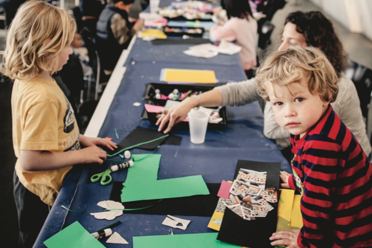 A child look at the camera while other children work on crafts.