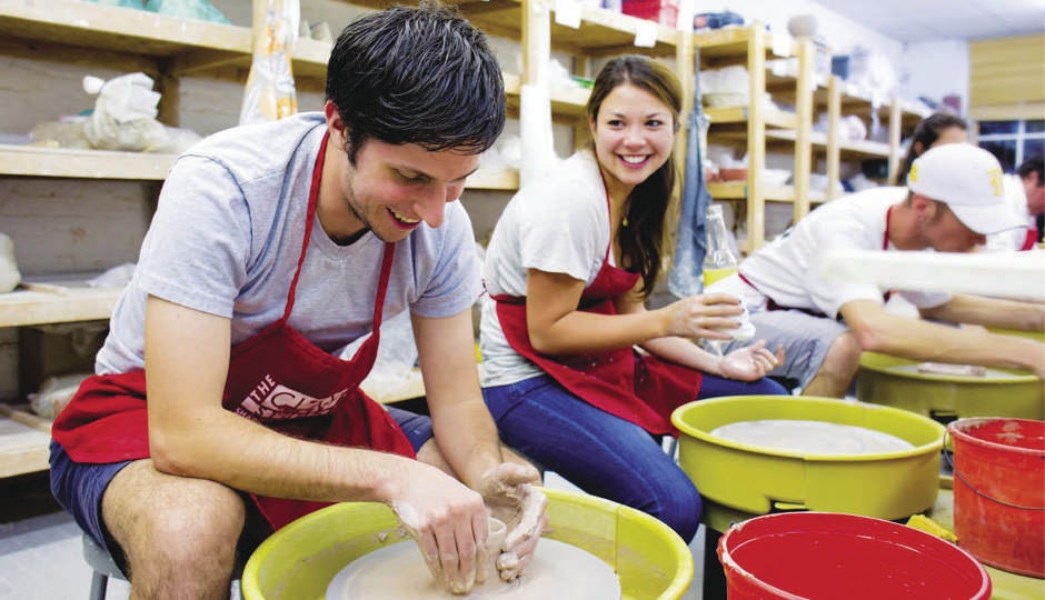 Two participants work on their clay art at a social pottery class.