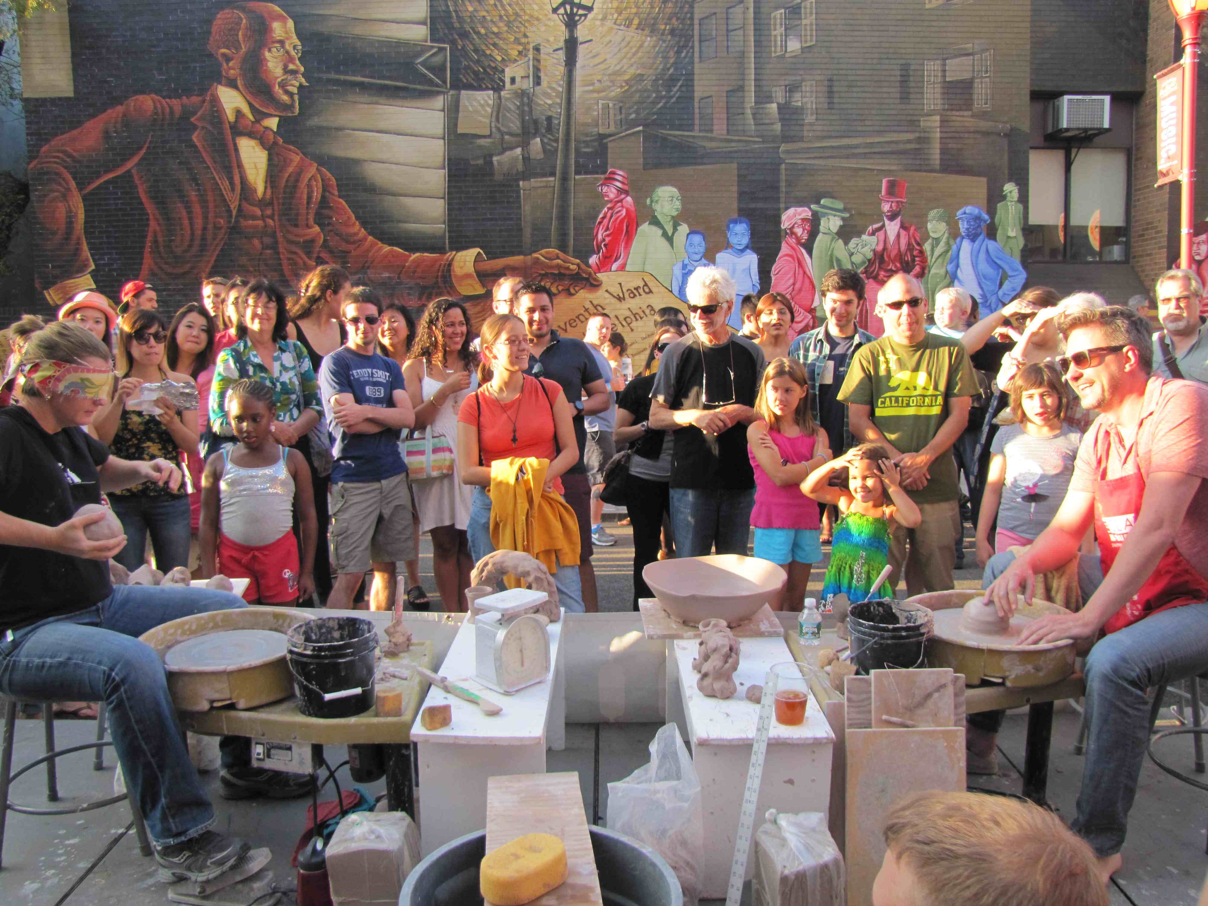 Two pottery throwers stand off in a game in front of an audience outdoors.