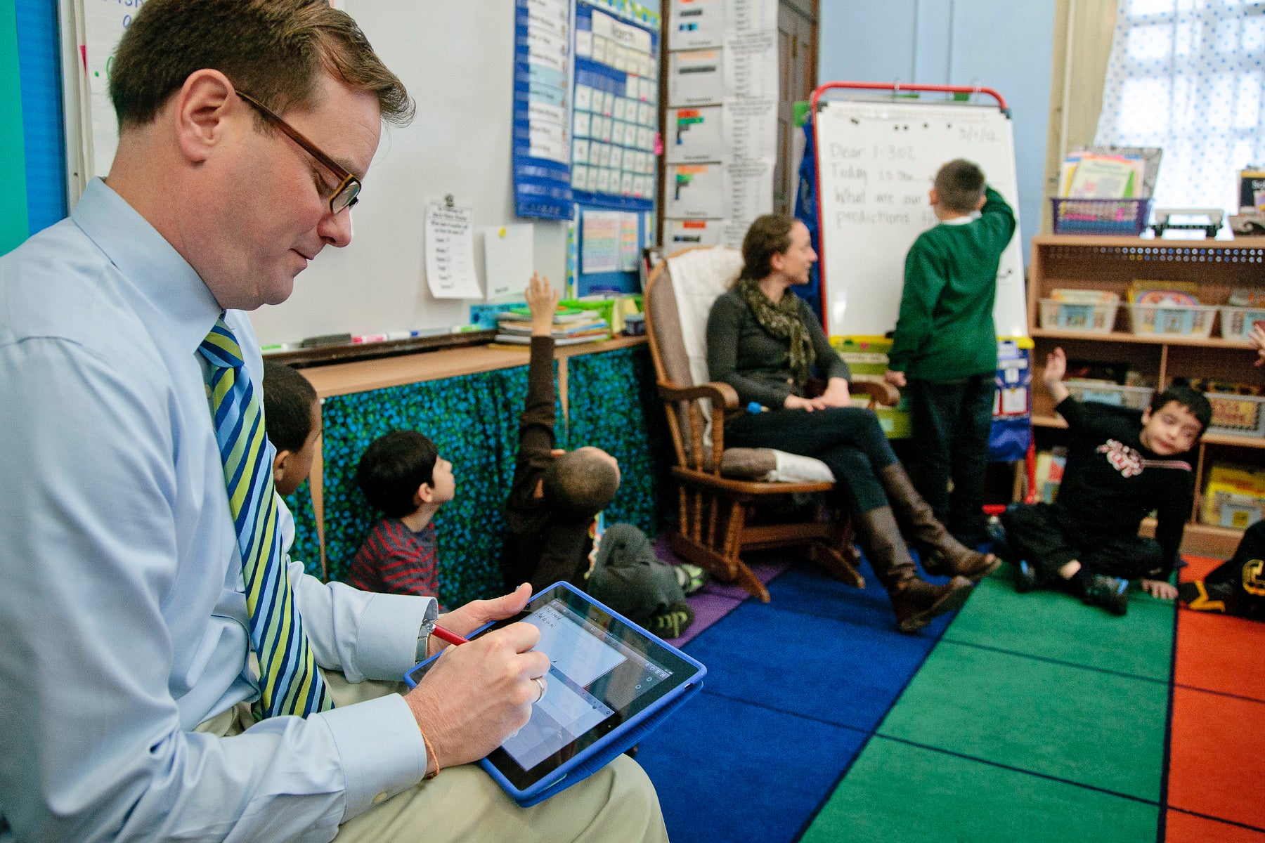 A principal takes notes as a class progresses.