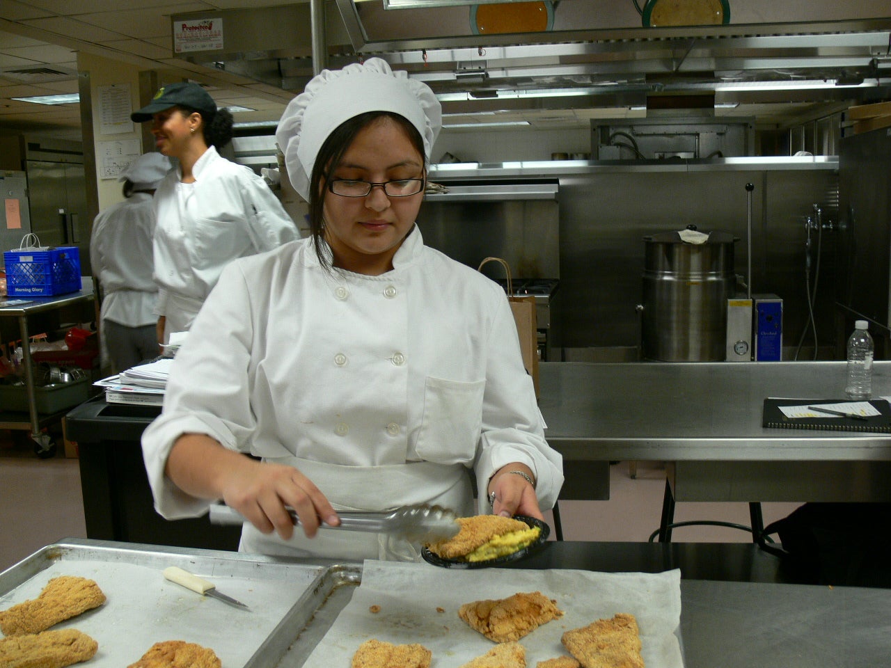 A high school student in chef's attire prepares meals.